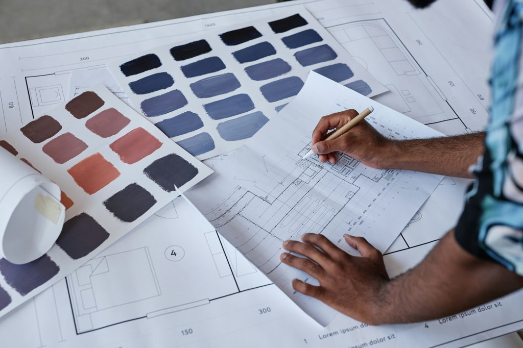 Male architect working on floor plans and color swatches